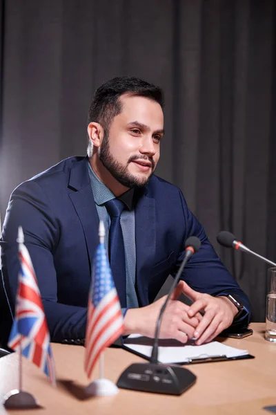 Pohledný kavkazský podnikatel sedí mluvící do mikrofonu na setkání — Stock fotografie