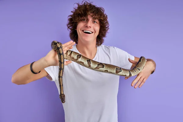 Dost canlısı kıvırcık erkek, elinde yılan tutuyor. — Stok fotoğraf