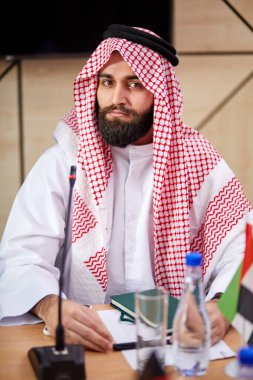 İş görüşmesinde geleneksel emirlik giysileri giyen yakışıklı, genç bir Arap.