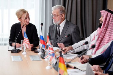 Takım elbiseli güzel beyaz kadın politik liderlerini dinliyor.