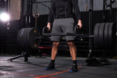 Kesilmiş güçlü kaslı, formda, spor salonunda ağır sıkletlerle antrenman yapıyor.