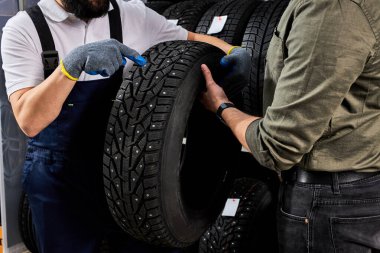 Yakışıklı beyaz lastik satıcısı ürünün karakteristik özelliklerinden bahsediyor.