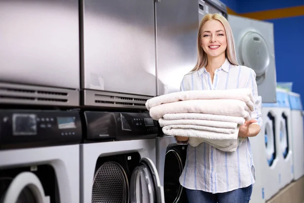 Молодая европейская белая женщина с светлыми волосами, улыбающаяся от счастья, выполняя работу в прачечной. — стоковое фото