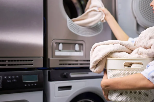 Молодая женщина достает чистую одежду из стиральной машины — стоковое фото