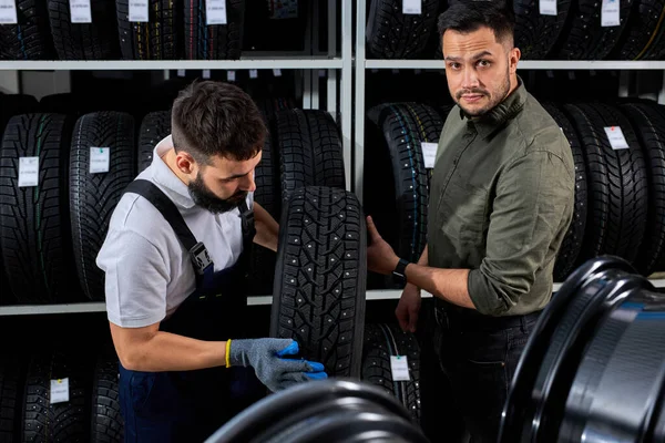 Handsome caucasian salesman of tires talking about characteristic of product — Stock Photo, Image