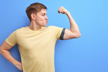 Kol kaslarını gösteren yakışıklı bir sporcu.