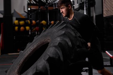 fit beyaz adam jimnastik salonunda lastiği döndürür, çapraz formda fonksiyonel spor