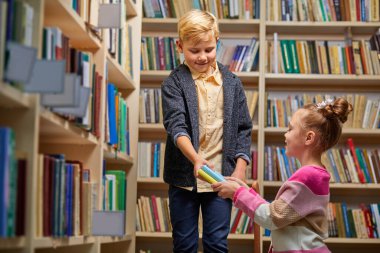 Erkek ve kız kütüphanede konuşuyor.