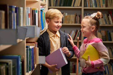 İki beyaz çocuk kütüphanede eğleniyor.