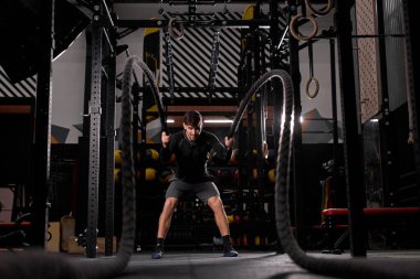 Modern spor salonunda atlet eğitimi sırasında Crossfit savaş halatları egzersizi