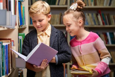 Kütüphanede kitap okuyan iki tatlı erkek ve kız çocuk.