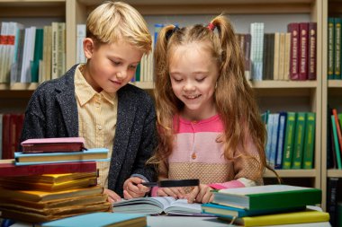 Kütüphanede kitap okuyan iki tatlı erkek ve kız çocuk.