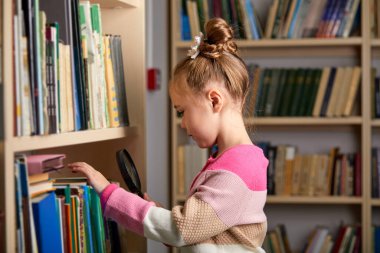 At kuyruklu güzel beyaz kız kütüphanede kitap seçiyor.