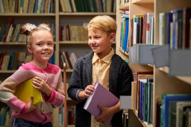 İki beyaz çocuk kütüphanede eğleniyor.