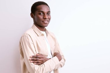 Kollarını kavuşturup gülümseyen kendinden emin Afrikalı bir adamın portresi.