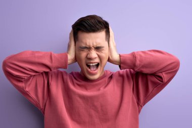 Sinirli adam kulaklarını kapatıyor, haberleri dinlemek istemiyor, kızgın.