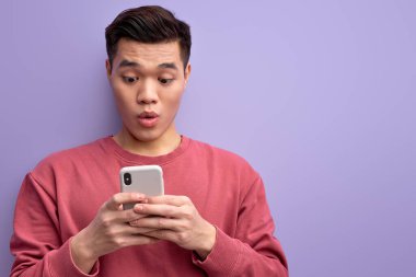 Asyalı duygusal bir adam akıllı telefondan biriyle konuşuyor, şokta duruyor.