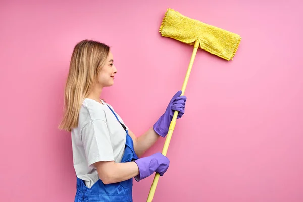 Side view on young housewife cleaning wall — Stock Photo, Image