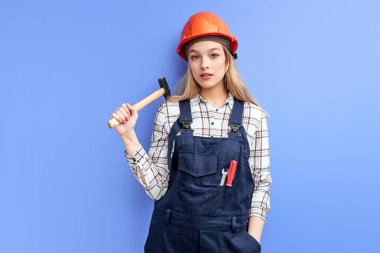 Kendine güvenen mimar kadın elinde çekiç tutuyor tamir etmeye hazır.