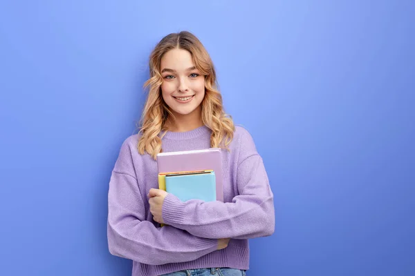 Alegre bela adolescente estudante menina segurar livros isolados no pastel azul fundo estúdio retrato — Fotografia de Stock