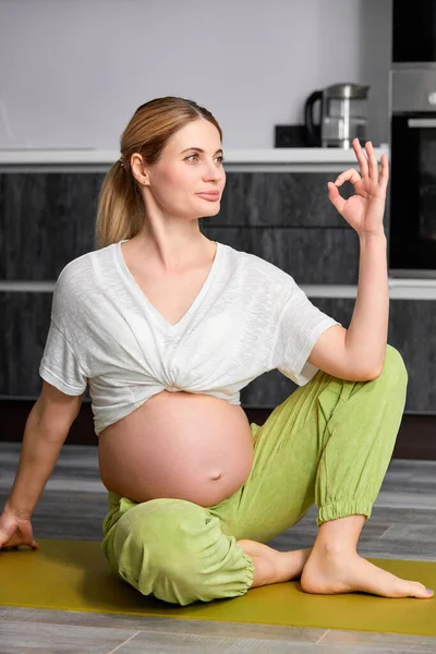 Relajada joven embarazada sentada en el suelo en casa, namaste, meditando — Foto de Stock