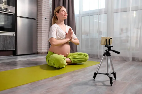 Гарненька блондинка Кавказька вагітна жінка робити вправи йога дивитися відео онлайн — стокове фото