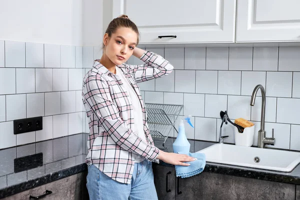 Sebevědomá žena myje kuchyňskou soupravu hadrem nebo hadrem. Dům profesionální úklid služby. — Stock fotografie