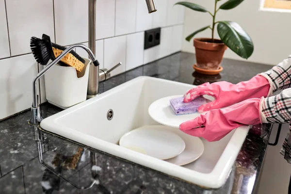 Platos de enjuague femeninos recortados con esponja púrpura por encima del fregadero — Foto de Stock