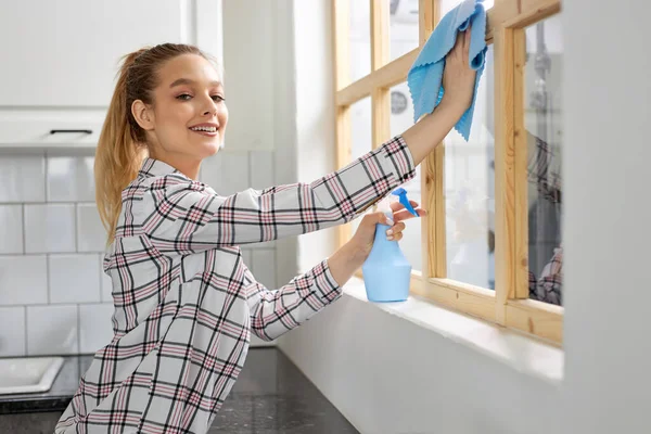 Lächelnde Frau wäscht Fenster mit Schwammtuch, putzt Fenster, wischt Schmutz ab — Stockfoto