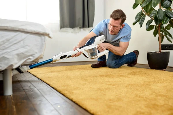 Piso de limpieza hombre con aspiradora en la moderna sala de estar blanca. Concepto de limpieza fácil con una nueva aspiradora moderna — Foto de Stock