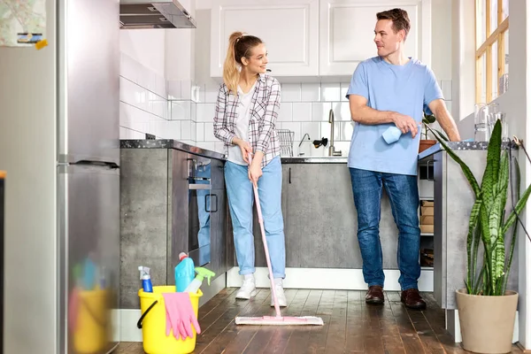 Fiatal szép gondnokok takarítás konyha és felmosó padló otthon — Stock Fotó