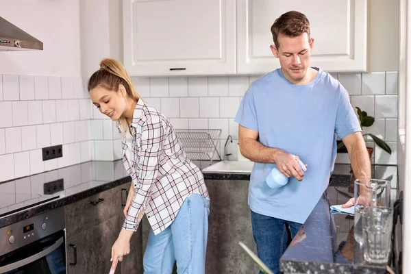 Két gondnok takarítja a konyhát és takarítja a padlót otthon. — Stock Fotó