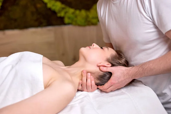Bonita hermosa mujer tumbada en la mesa de masajes y disfrutando del masaje profesional — Foto de Stock