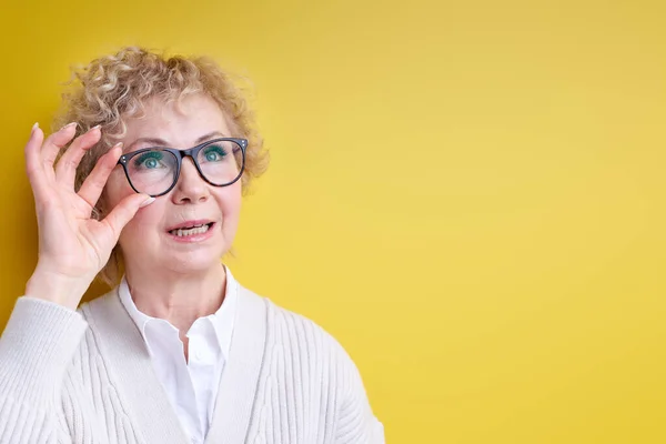 Překvapená vnímavý starší žena při pohledu na straně upevnění brýle — Stock fotografie