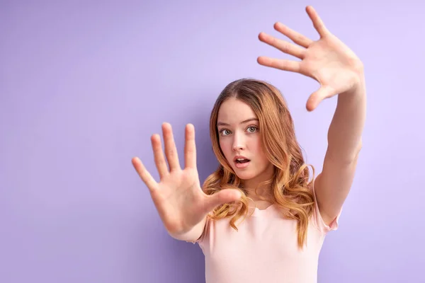 Έφηβος κορίτσι πάνω από απομονωμένο μωβ φόντο φοβάται με τα χέρια ψηλά σαν κάτι που πέφτει από πάνω — Φωτογραφία Αρχείου