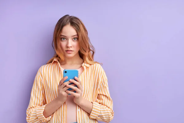 Красивая целеустремленная девушка с помощью сотового веб-приложения изолированы на фиолетовом фоне — стоковое фото