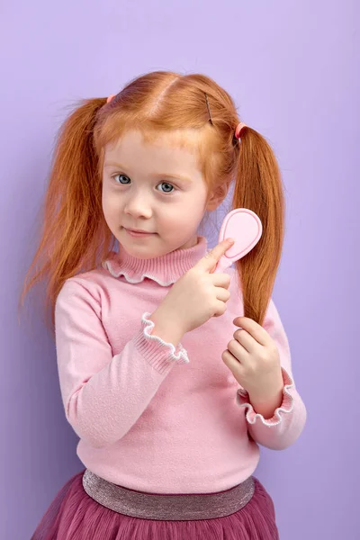 Caucásico pelirroja niña peinando pelo posando en cámara —  Fotos de Stock
