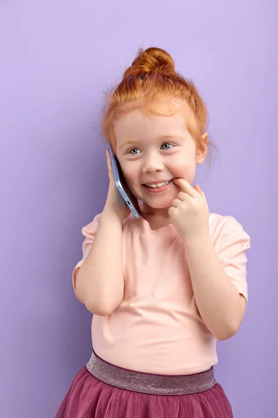 Trevligt barn håller mobiltelefon, ler, har trevligt prata med någon — Stockfoto