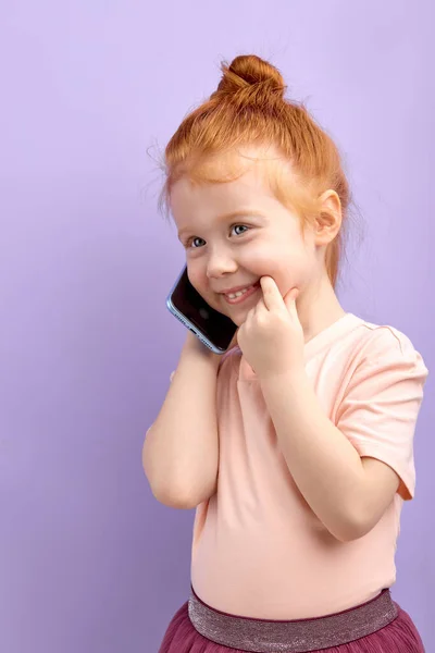 Aranyos gyerek, mobiltelefonnal a kezében, mosolyog, kedves beszélgetést folytat valakivel. — Stock Fotó