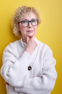 Ciddi ve konsantre görünüşlü, beyin fırtınası yapan ve zorlu sorunları düşünen yaşlı bir kadın.