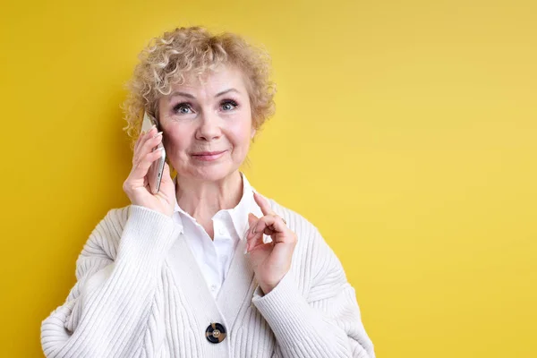 Starší žena mluví po telefonu, soustřeďuje se na myšlenky a poslouchá řeči — Stock fotografie