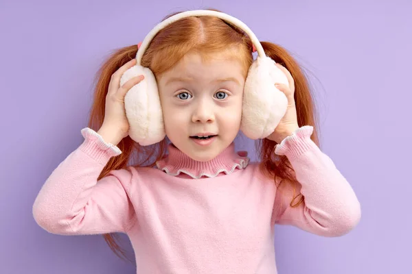 Όμορφο κοριτσάκι με κόκκινα μαλλιά σταθεί φορώντας ασύρματα ακουστικά, να απολαύσετε ακούγοντας μουσική — Φωτογραφία Αρχείου