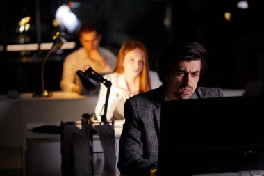 Kararlı iş adamı geç saatlere kadar çalışarak zor bilgisayar görevlerine konsantre oldu.