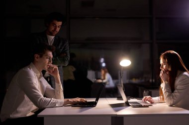 Geceleri kurul odasında çalışan yaratıcı insanlar, bilgisayar üzerinde çalışan iş arkadaşları.