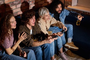 Çeşitli heyecanlı arkadaşlar evde, içeride oyun konsolu oynayarak eğleniyorlar. Arkadaşlık, kira, dinlenme, ev partisi konsepti.