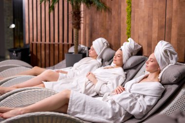 Kafkas kadınlar bornoz ve havlular içinde, spa merkezinde yatağa uzanmış, dinleniyor, zaman geçiriyorlar.