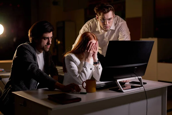 Responsive colleagues helping supporting redhead woman at work, at night in office