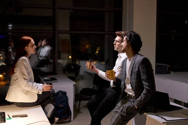 Вид збоку на хороших офісних працівників, колеги розмовляють після важкого робочого дня — стокове фото