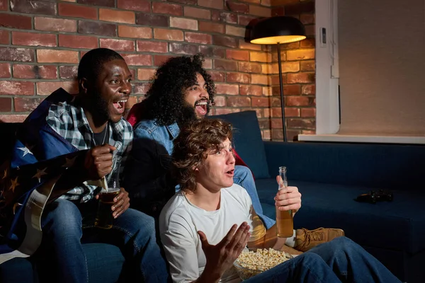 Chicos relajados viendo partidos de fútbol en casa. Grupo multiétnico de amigos, fans animando a la selección nacional favorita — Foto de Stock