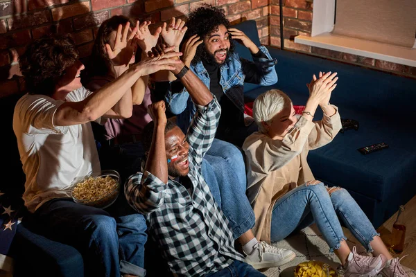 Jóvenes fanáticos del fútbol se reunieron para animar mientras veían fútbol u otro juego deportivo en casa — Foto de Stock